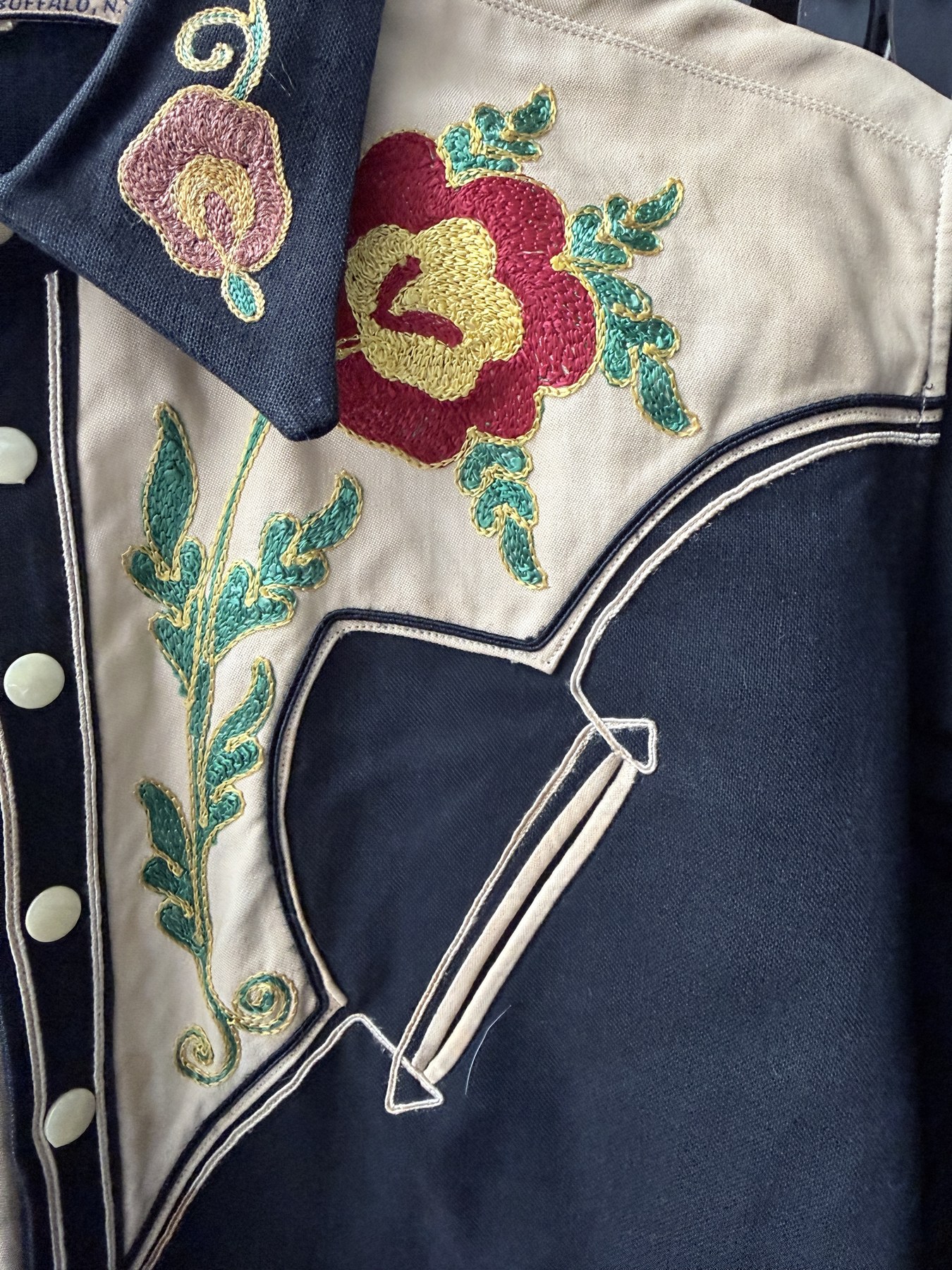 Close view of the cream yoke, rose embroidery, double piping and arrow-tipped pocket of the Sam A. Formann Co. shirt