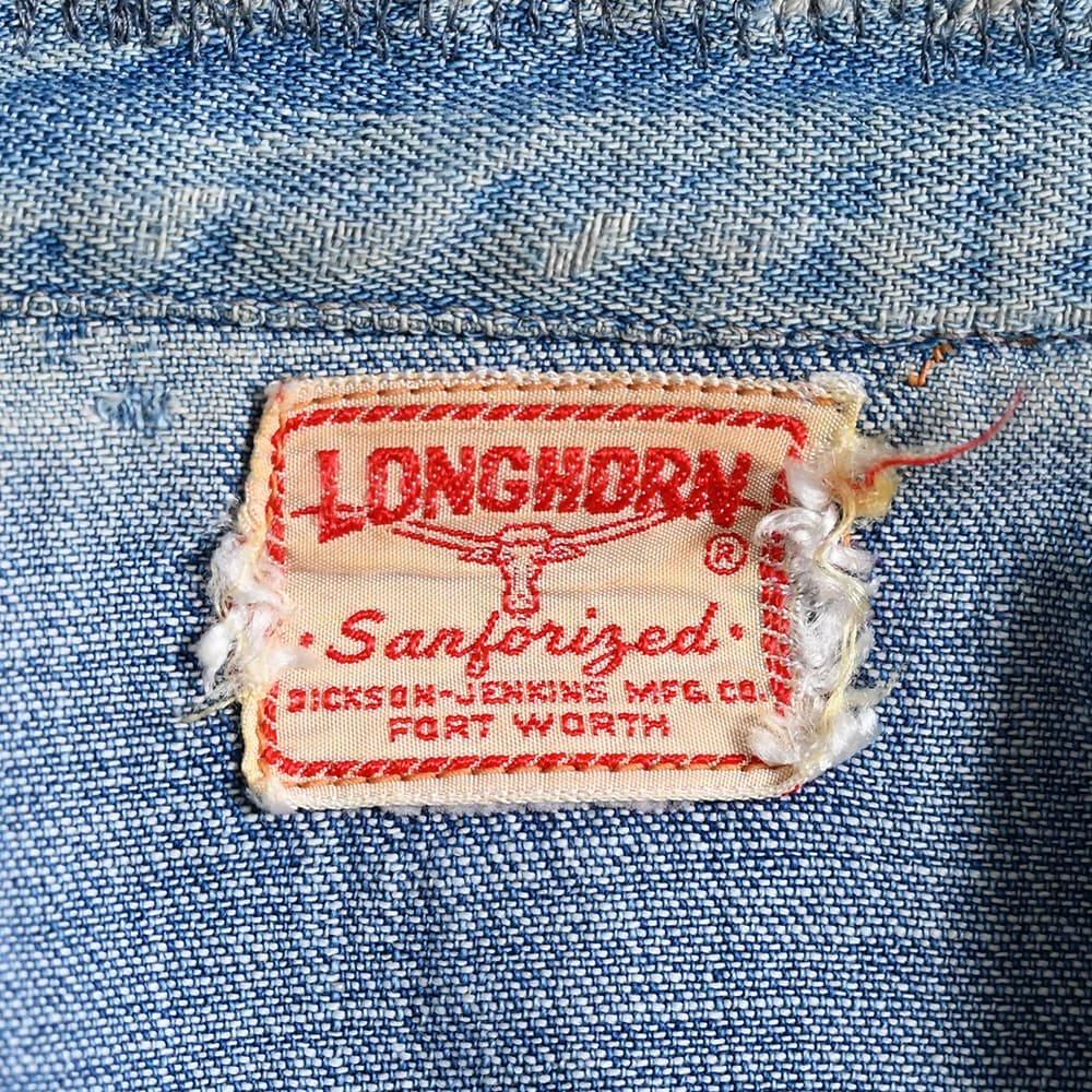 Close seller view of a sewn Longhorn Sanforized label with Dickson-Jenkins Mfg. Co. and Fort Worth wording. The label is evidence on this shirt, not a complete company history.
