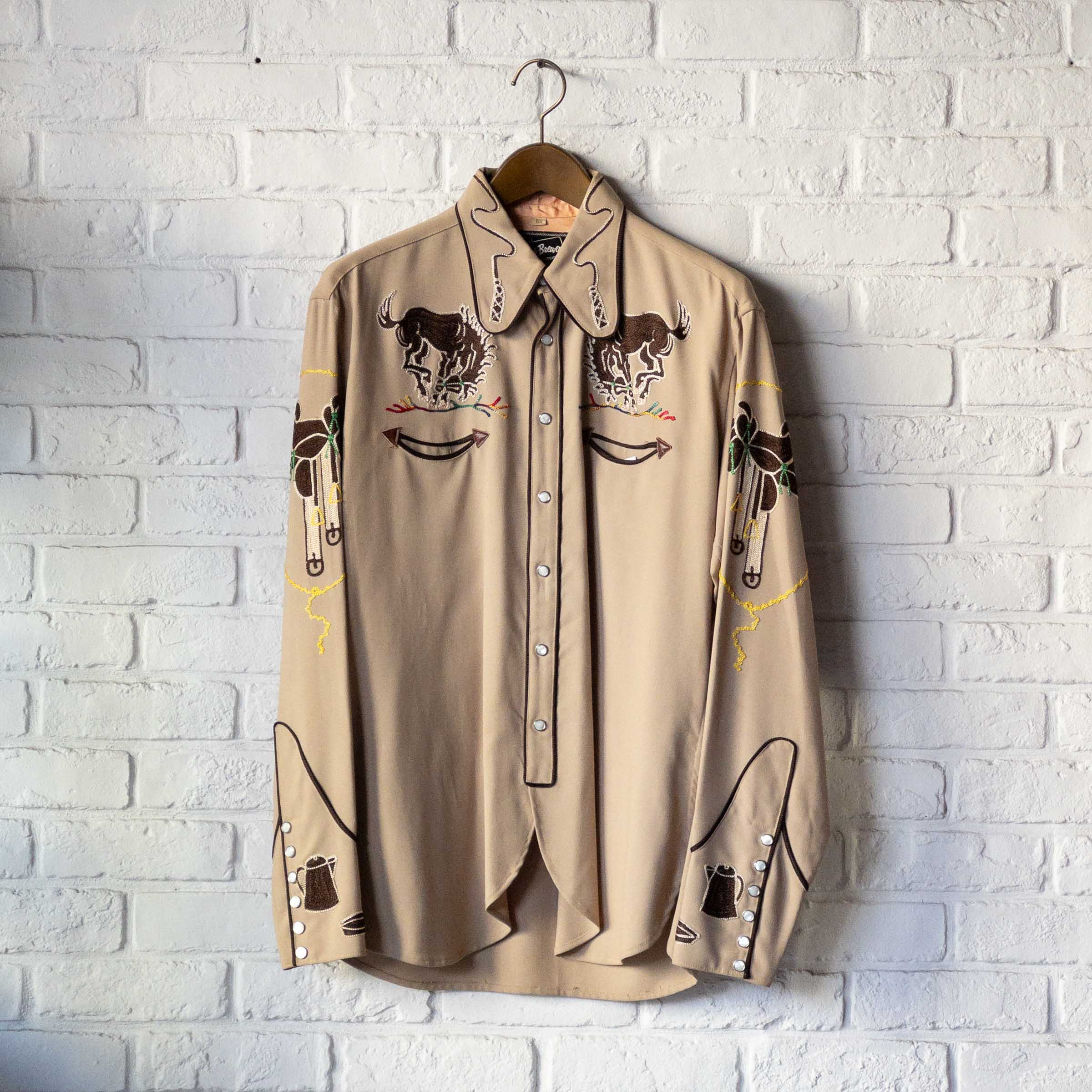 Dealer view shows an embroidered Western shirt with bucking-horse and saddle motifs. The dealer’s period and dead-stock descriptions remain unverified.